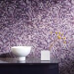 mosaico di piastrelle con sfumature sulle varie tonalità del viole nel muro di un bagno dietro ad un lavabo