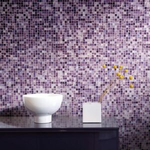 mosaico di piastrelle con sfumature sulle varie tonalità del viole nel muro di un bagno dietro ad un lavabo
